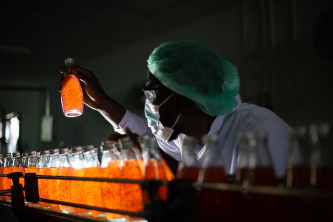 Man checking orange drink bottles at factory