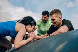 Woman in an obstacle course climbing a drum
