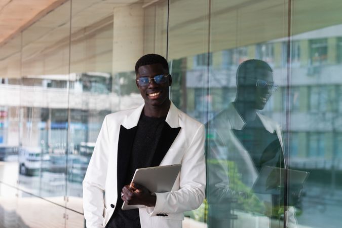 Content Black businessman in stylish apparel with tablet outdoors