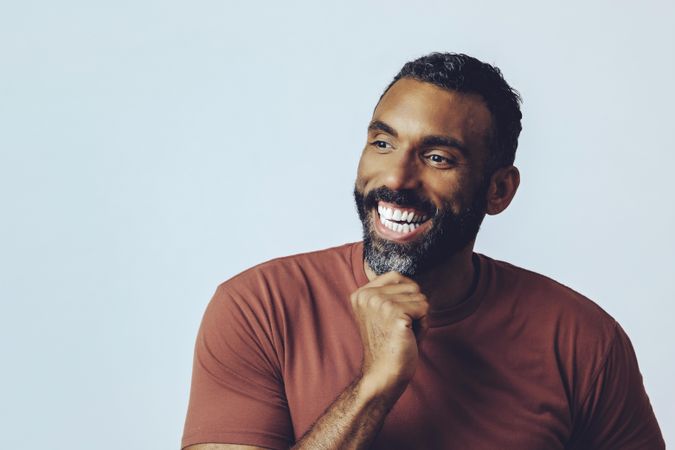 Head shot of happy Black male looking away in grey studio