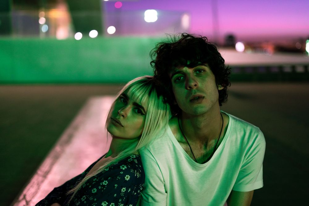 Loving couple sitting against vibrant sky