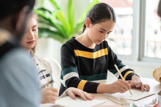 Young female student concentrating on writing in class