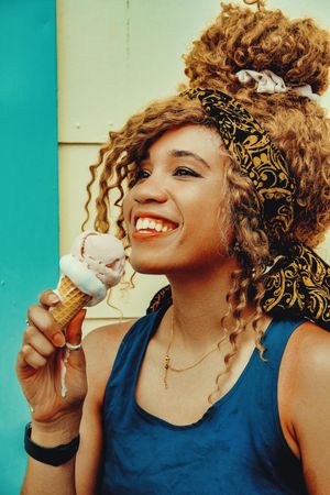 Vertical shot of happy Black female enjoying an ice cream cone in the sun