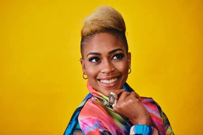 Studio shot of confident Black woman in bold 80s windbreaker jacket looking away with hand on chin