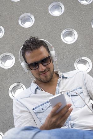 Smiling male using headphones while looking at phone