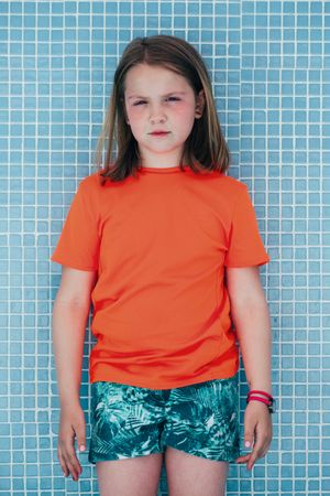 Serious girl standing against tiled wall
