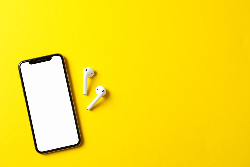 Phone with empty screen on yellow background, top view