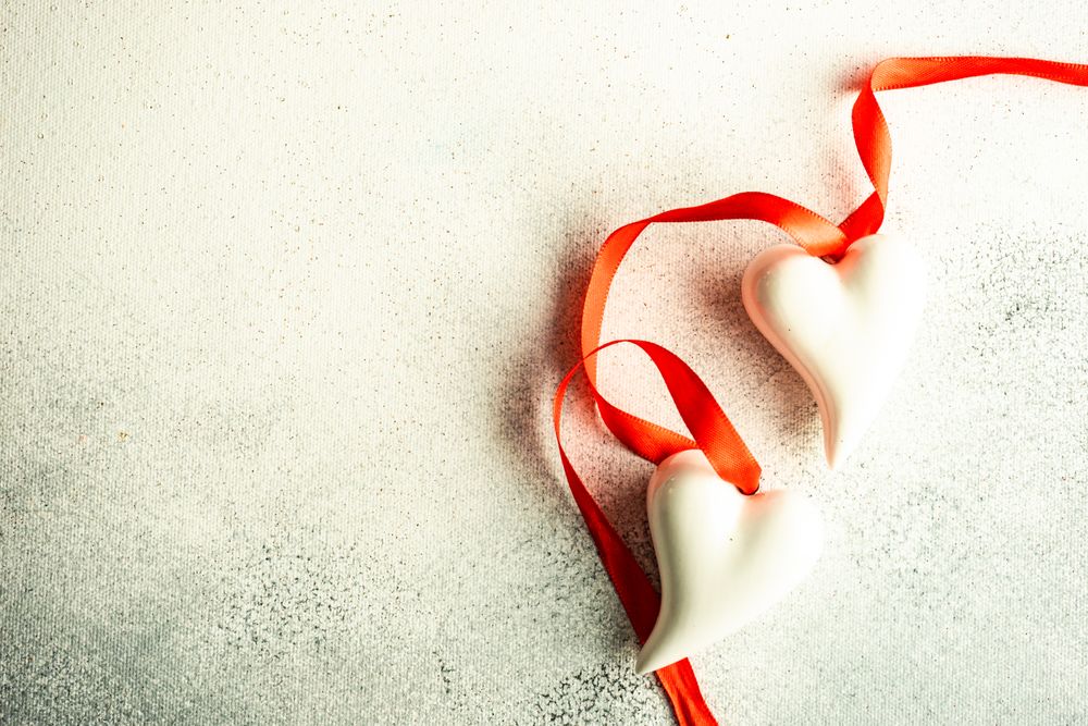 Ceramic heart decorations with red ribbon on grey counter