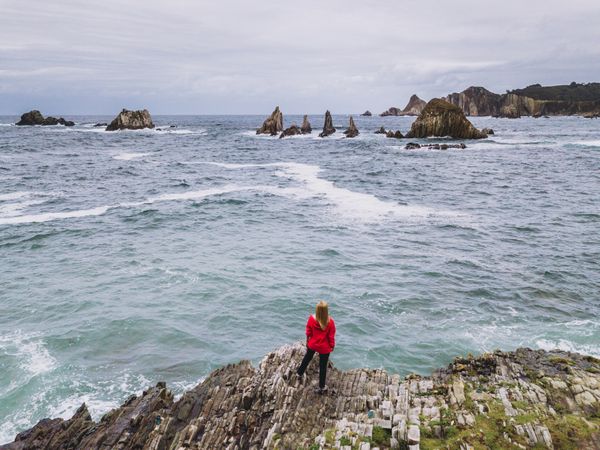 Woman standing on stony green seashore