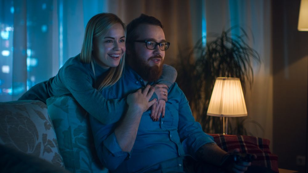 In the Evening Man Sitting on a Sofa Playing Videogames