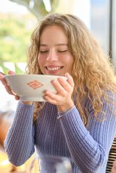 Positive young female and eating soup in restaurant