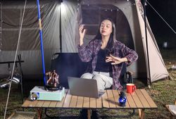 Young Asian Woman Using laptop in front of Camping Tent