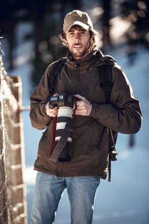 Man with camera in winter forest