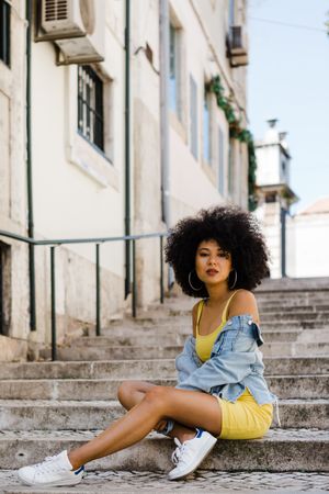 Stylish female sitting in stairs with railing outdoors