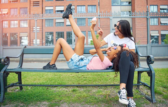 Happy friends enjoying day outside taking selfies together at a park