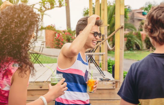 Laughing friends with fruity cocktails outside