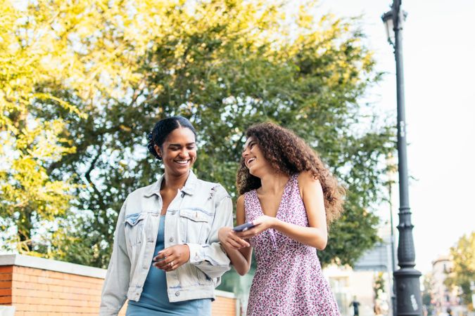 Black Latina friends using a smartphone in the park.