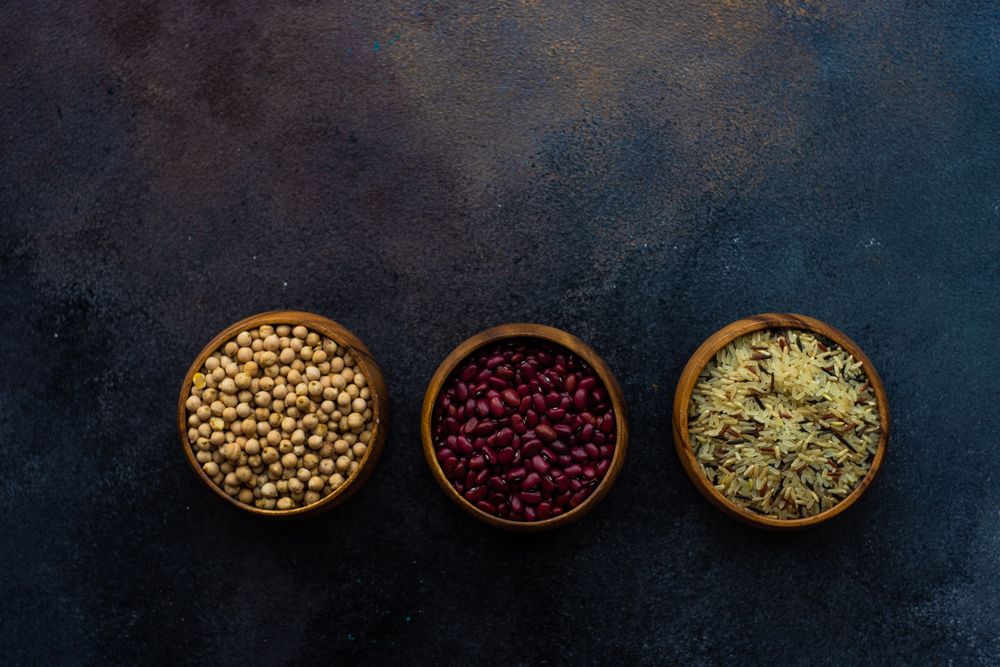 Top view of dry beans and rice in bowls on grey counter with copy space