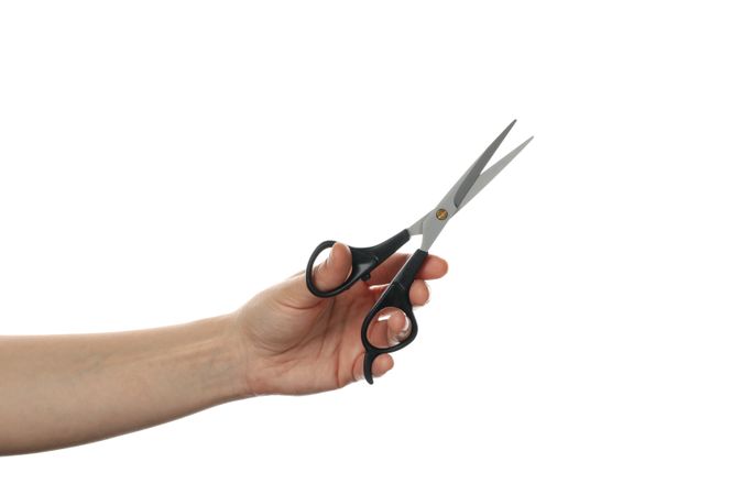Female hand holds hairdresser scissors, isolated on plain background