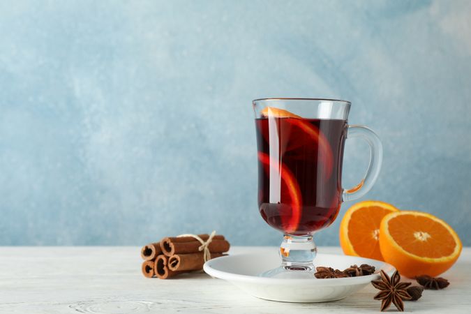 Mulled wine, orange and cinnamon on blue wooden background, space for text