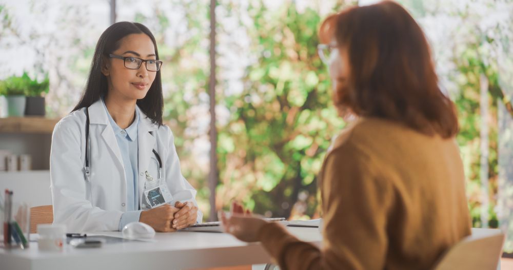 Asian Healthcare Professional Listening to a Female Patient Before Prescribing Treatment for Her Medical Condition During a Consultation in a Health Clinic