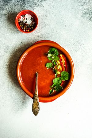 Top view of tomato soup in ceramic bowl served with salt and pepper