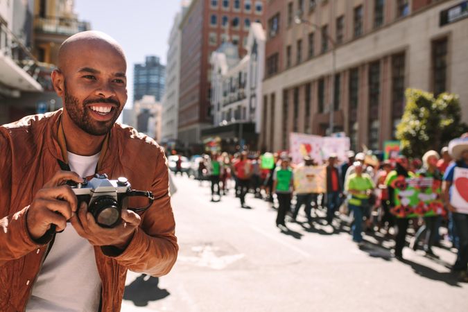 Smiling male photographer takes pictures of activists on road