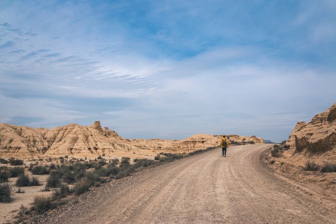 Man walking on road in desert hills
