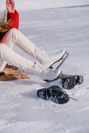 Woman sitting on snow and changing boots