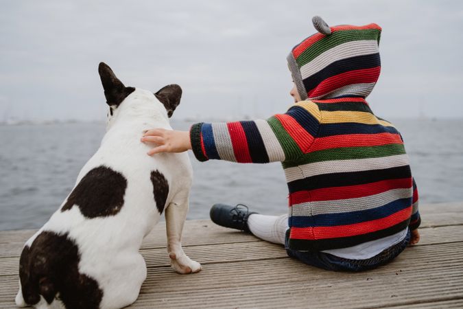 Anonymous kid petting dog on pier