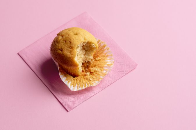 Muffin partially eaten on pink background