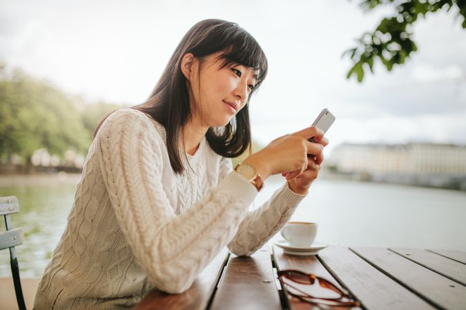 Shot of beautiful asian woman using mobile phone at cafe