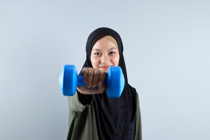 Sporty Muslim Indonesian Woman training with Blue Dumbbells