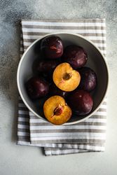Top view of bowl of halved ripe plums