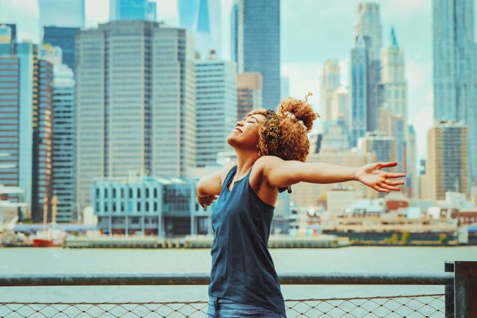 Happy Black woman with her arms open with Hudson River in the background, copy space