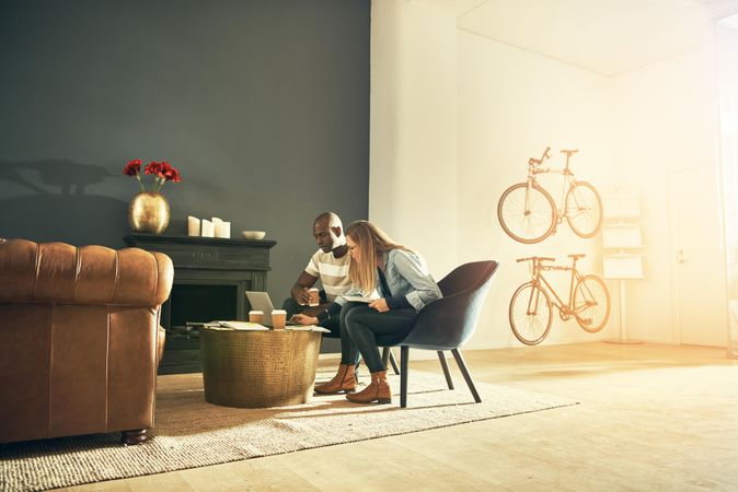 Male and female colleagues focused on laptop in modern workspace