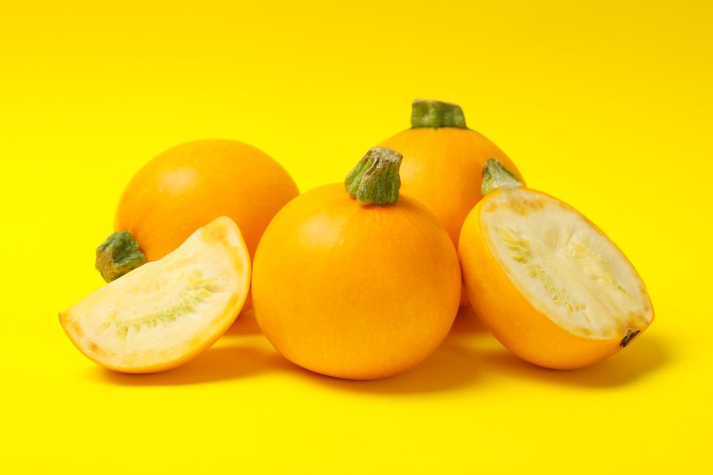 Bunch of round zucchini on yellow background