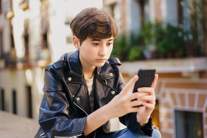 A teenage girl absorbed in her mobile phone in a vibrant urban setting, candidly captured