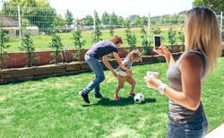 Mother taking photo of her husband and son playing