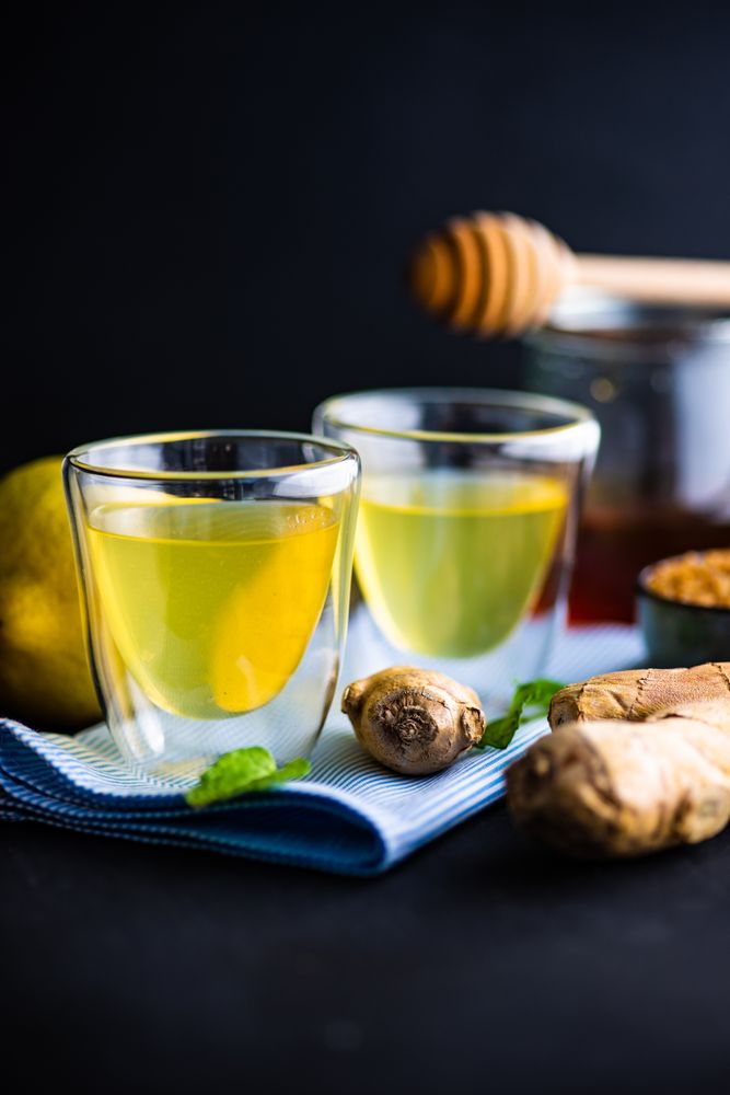 Close up side view of detox shots on napkin with lemon, ginger and mint on napkin
