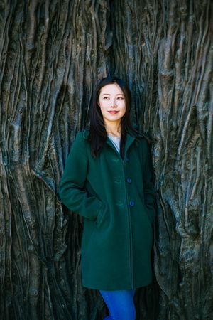 Pensive Asian woman leaning on rough wall