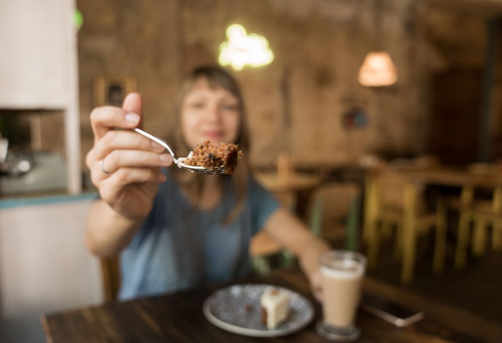 Woman holding spoon with slice of cake