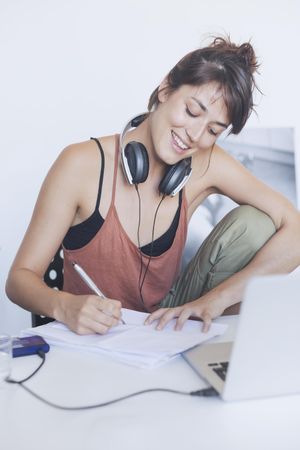 Happy woman sitting at desk writing something out on paper