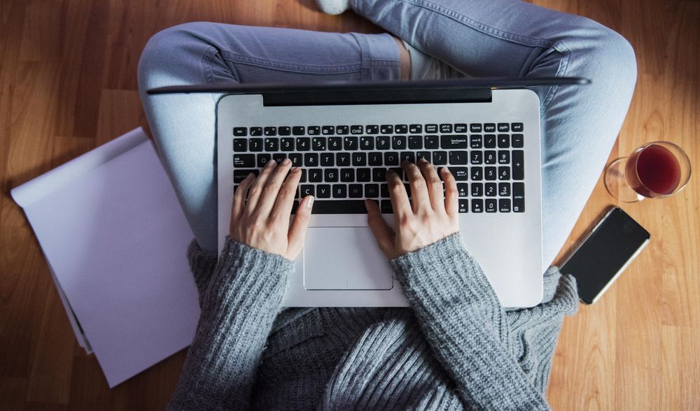 Woman working on laptop while sitting on the floor