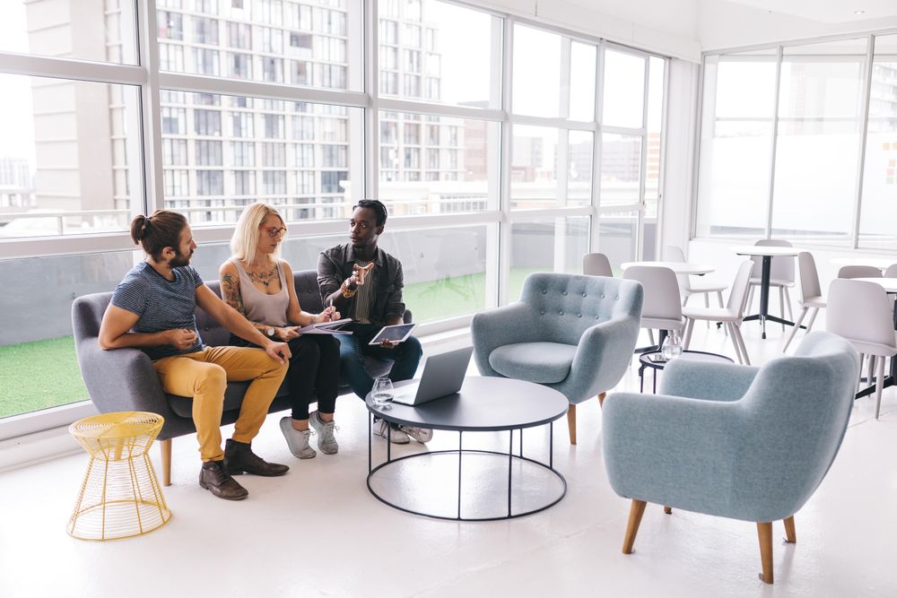 Group of co-workers sitting and having a discussion with a laptop and tablet