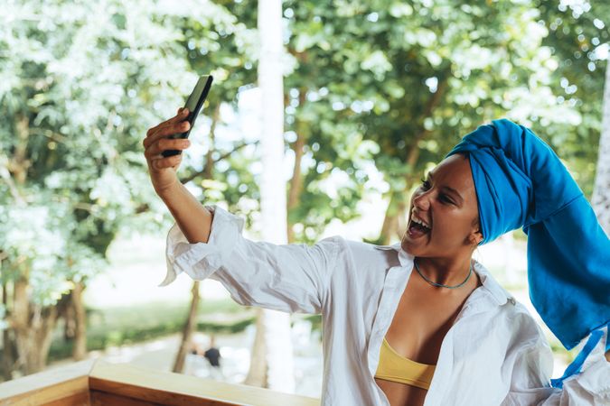 Positive woman with turban on head taking selfie on sunny street
