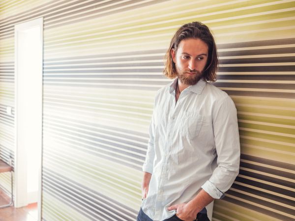 Handsome male standing with hand in pockets in modern room