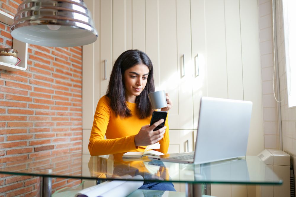 Persian female working at home with a laptop and coffee in hand