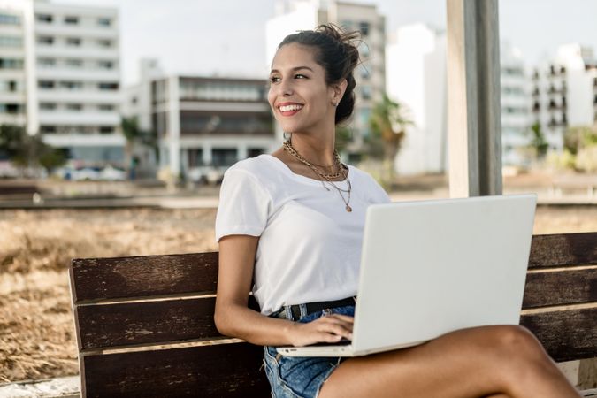 Woman working on her laptop sitting on a bench outdoor