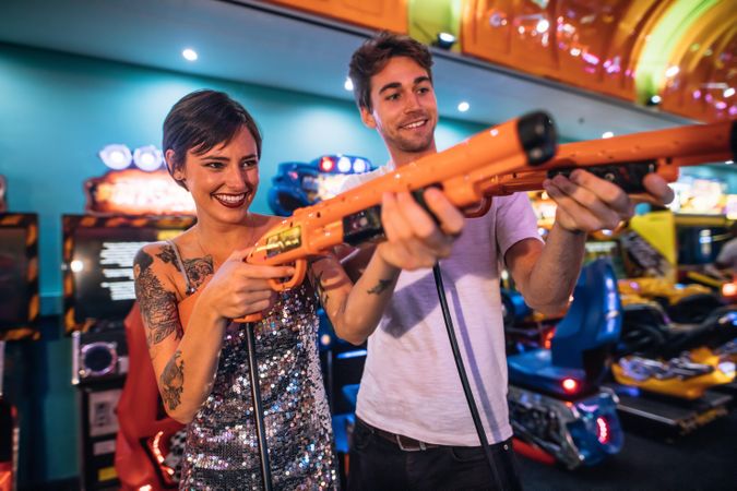 Man and woman playing shooting games with gaming guns at a gaming arcade